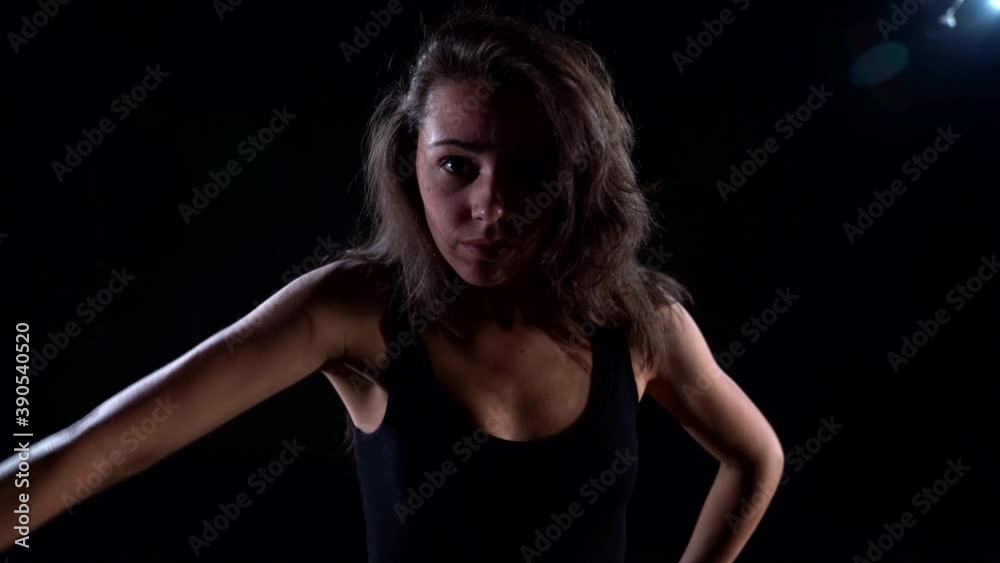 Portrait of a young energetic, plastic woman in a black suit in a Studio on a dark background dancing, moving and posing. Portrait of a young energetic, plastic woman in a black suit in a Studio on a dark background dancing, moving and posing.