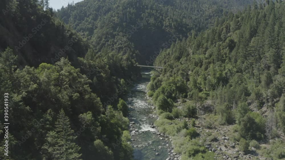 Slow forward drone flight over a rocky river toward a tall bridge Slow forward drone flight over a rocky river toward a tall bridge