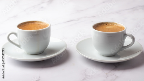 two white cups with black coffee on a white background.