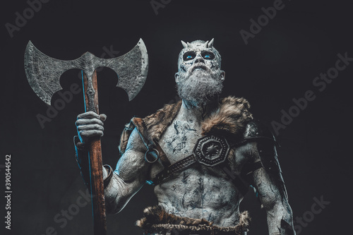 Tela Armed with two handed axe dead northern chief in dark armour with fur and with pale skin in dark background