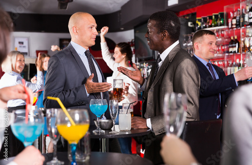 Portrait of African and Caucasian men having fun and talking on corporate party