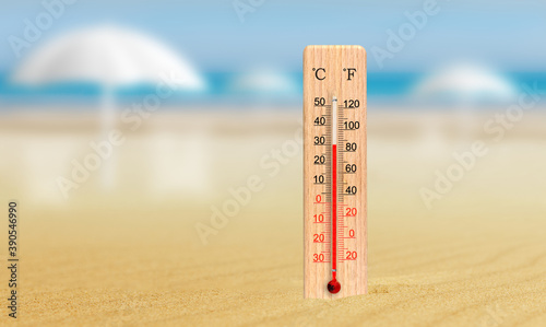 Sea coast at hot summer day. Wooden thermometer in the sand. Ambient temperature plus 30 degrees celsius photo