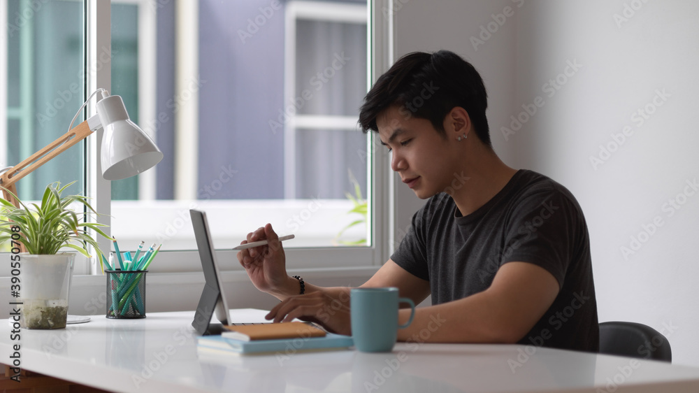 Male working with digital tablet and stationery on worktable in home office Male working with digital tablet and stationery on worktable in home office