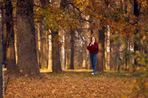 Autumn forest nature. woman stands under a tree on fallen leaves. © Aleksandr