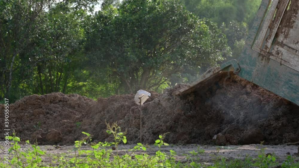 Heavy duty dump truck dumping soil, road works Heavy duty dump truck dumping soil, road works