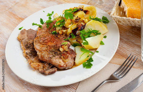 Tasty steaks of pork loin served with homestyle boiled potatoes, fried chopped onion and greens