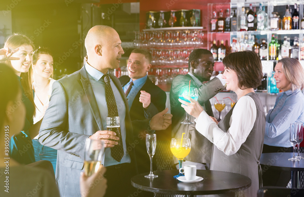 Friendly coworkers having pleasant conversation and flirting at office party in nightclub