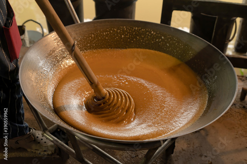 Asian man making boiled palm coconut sugar or cane production process, raw material, Amphawa, Thailand. Traditional culture lifestyle. Local sweet food. photo