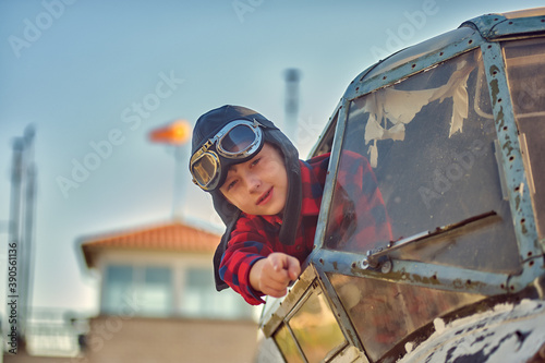 Portrait of a happy boy in a flying retro helmet in the cockpit of an old plane