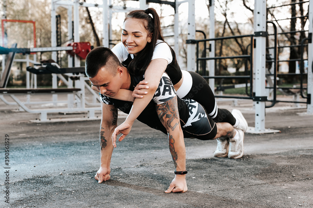 Obraz premium trong athletic man does push-UPS with his girlfriend on the outdoor