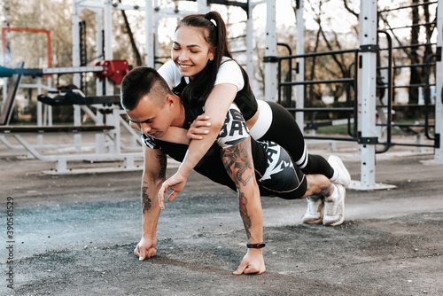 trong athletic man does push-UPS with his girlfriend on the outdoor