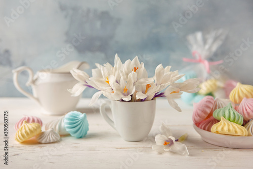 Still life with a bouquet of crocuses, a plate of colorful meringues and a milkman . Good morning greeting card.