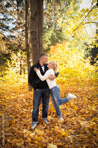 Happy couple having fun outdoors in autumn park. People on the background of yellow blurry leaves