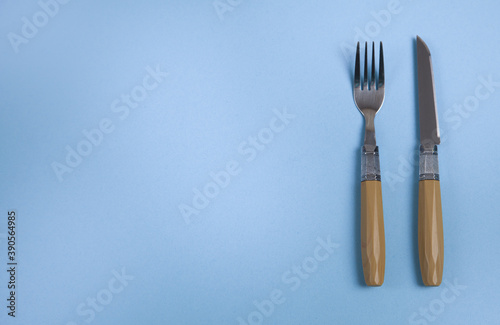 Knife and fork on an isolated blue background.