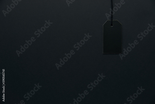 Blank black cardboard paper label or price tag with cord isolated on dark background. Black Friday, Shopping, sale and marketing concept. Top view, flat lay, copy space. .