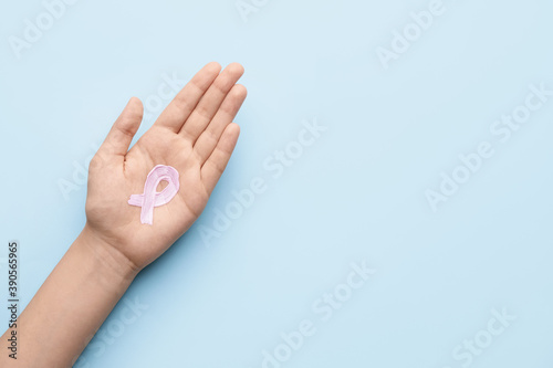 Female hand with pink ribbon on color background. Breast cancer awareness concept