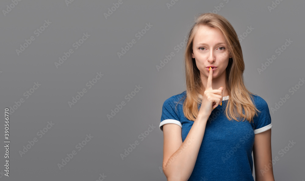 Pretty young blonde woman keeps finger on lips. Shh, silence concept. Copy space Pretty young blonde woman keeps finger on lips. Shh, silence concept. Copy space