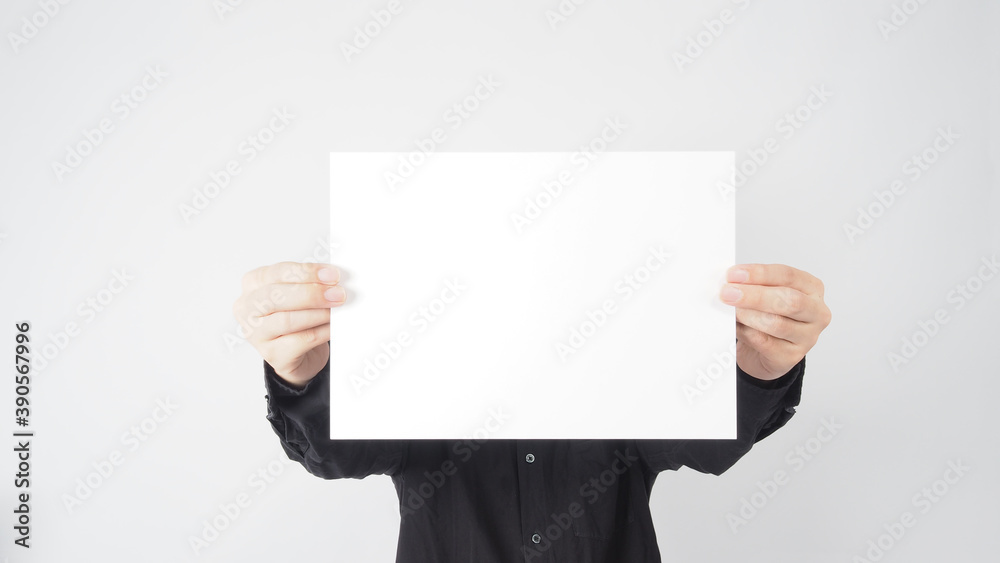 Empty space for text.Male asian wear black shirt and hand is holding the A4 paper on white background. Empty space for text.Male asian wear black shirt and hand is holding the A4 paper on white background.