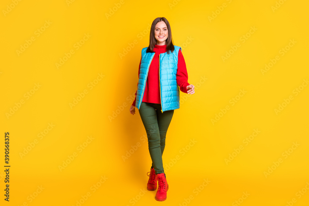 Full body size photo of cute lovely young lady beaming smiling elegantly walking tiptoes towards you wear green pants blue vest red sweater boots isolated bright yellow color background Full body size photo of cute lovely young lady beaming smiling elegantly walking tiptoes towards you wear green pants blue vest red sweater boots isolated bright yellow color background