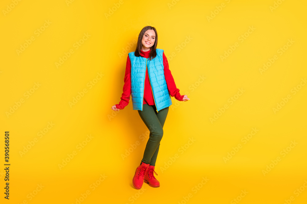 Full body size photo of charming pretty young lady fists sleeves beaming smiling girlish shy posing wear green trousers blue vest red sweater boots isolated bright yellow color background