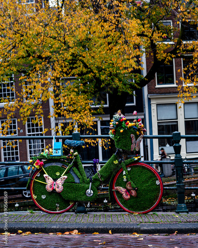 Photography Colorful decorated bike parked against a railing of a Amsterdam canal bridge wit