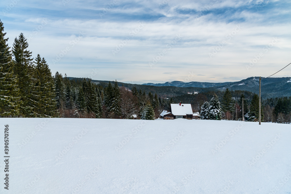 Winter Moravskoslezske Beskydy mountains in Czech republic with isolated house, snow covered meadow, forest and hills on the background