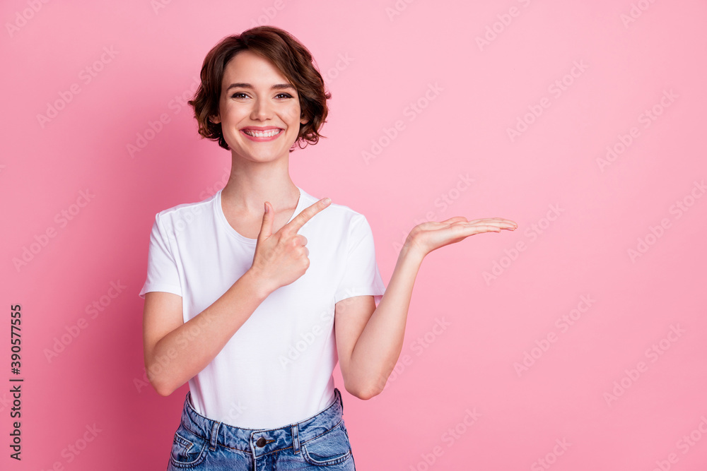 Portrait of attractive cheerful brown-haired girl holding on palm showing advert copy space isolated over pink pastel color background Portrait of attractive cheerful brown-haired girl holding on palm showing advert copy space isolated over pink pastel color background