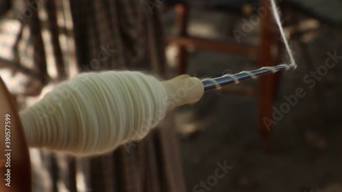 Home made yarn spinning at high speed on a bobbin attached to a spinning wheel. photo