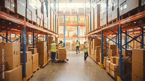 Retail Warehouse full of Shelves with Goods in Cardboard Boxes, Workers Scan and Sort Packages, Move Inventory with Pallet Trucks and Forklifts. Product Distribution Delivery Center. photo