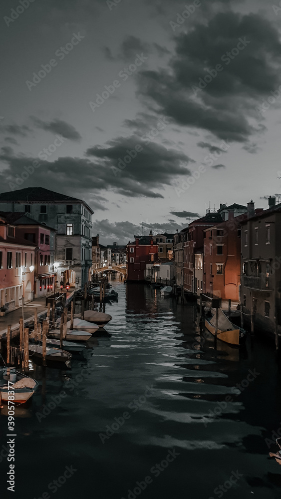 CHIOGGIA, ITALY - Jun 27, 2020: summer night in Chioggia, Veneto, Italy. The main canal that crosses the center the fishing boats and the pedestrian streets on the sides.