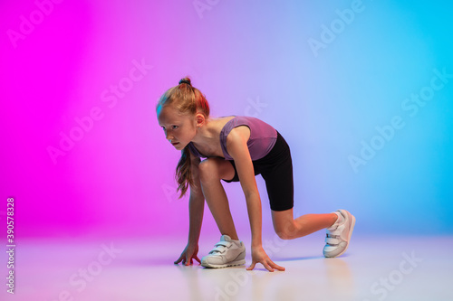 Ready. Teenage girl, professional runner, jogger in action, motion isolated on gradient pink-blue background in neon light. Concept of sport, movement, energy and dynamic, healthy lifestyle.
