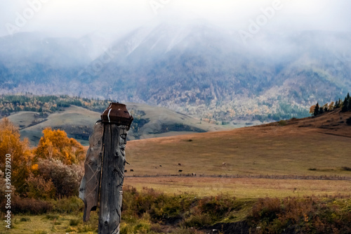 Wooden totem pillar on mountains background in autumn. Orthodox old believers totem. Religious symbol.