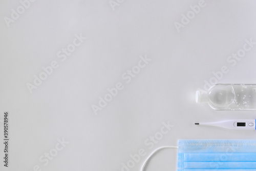 white thermometer lies on a light background antiseptic and a blue mask