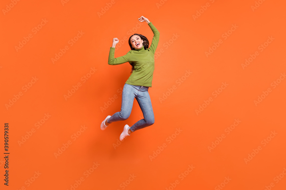 Full body photo of young excited girl celebrate win victory goal fists hands jump isolated over orange color background