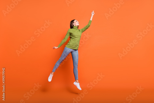 Full length photo of young active woman happy smile try catch umbrella jump isolated over orange color background