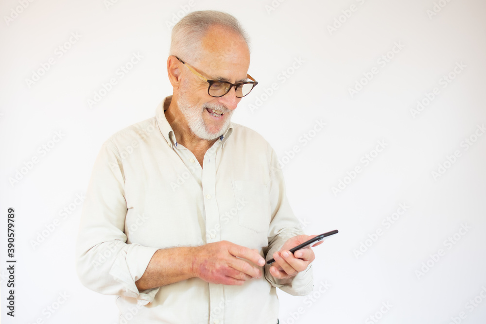 Studio shot of happy senior bearded businessman smiling while using mobile phone with eyeglasses against white background