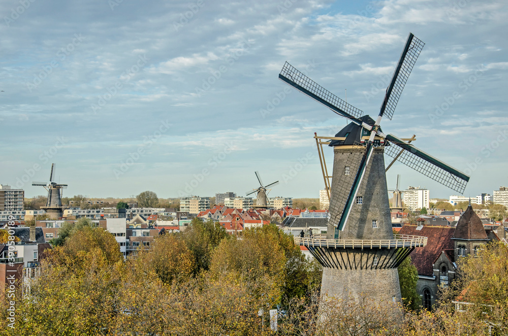 Schiedam, The Netherlands, October 31, 2020: windmill De walvisch (The Whale) with moving sails, with the old town and three more windmills in the background