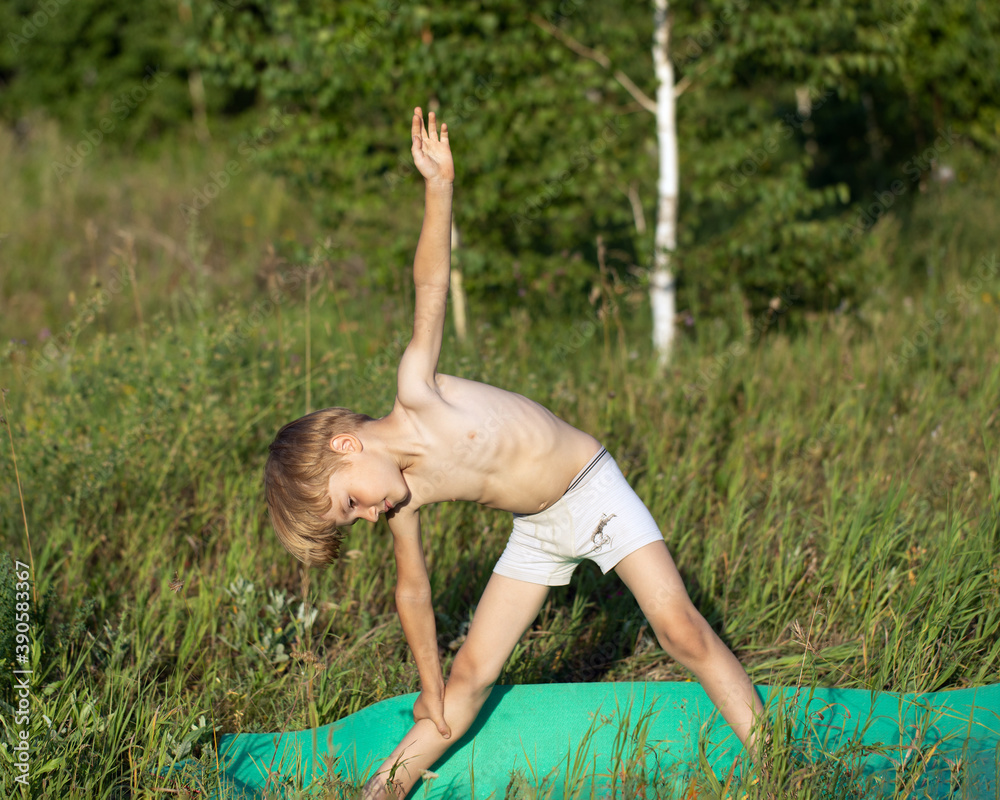 Cute boy child practices yoga in Utthita Trikonasana, extended triangle