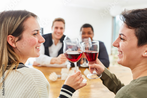Glückliche Freunde prosten sich zu mit Glas Wein zu Hause
