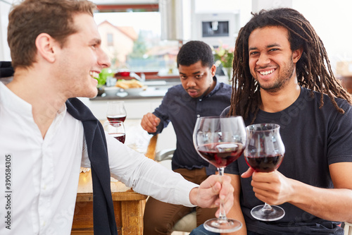 Männer als Freunde in WG Küche stoßen mit Glas Rotwein an