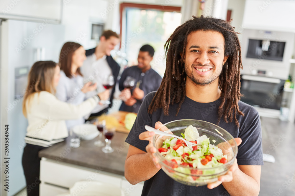 Mann mit frischem Salat in Schüssel in Küche für Essen mit Freunden