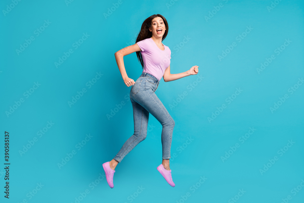 Full length profile photo of funky pretty girl jump run open mouth wear pink t-shirt footwear jeans isolated blue color background