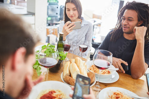 Freunde beim Essen am Tisch macht Foodie Bilder und schaut auf Smartphone
