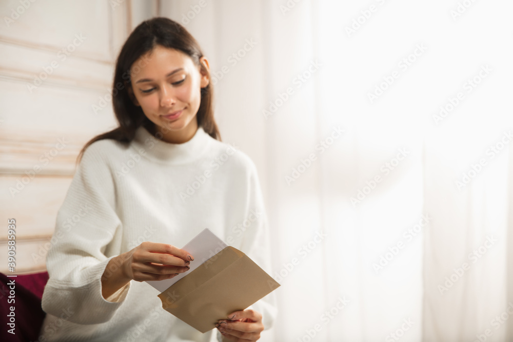 Woman opening, recieving greeting card for New Year and Christmas 2021 from friends or family. Reading a letter with best wishes, looks happy, cheerful, smiling, opening envelope. Holidays Woman opening, recieving greeting card for New Year and Christmas 2021 from friends or family. Reading a letter with best wishes, looks happy, cheerful, smiling, opening envelope. Holidays