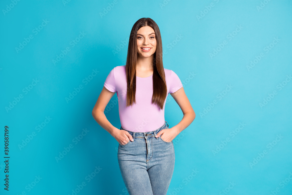 Photo of adorable lovely student girl wear casual violet t-shirt denim pants arms hands pockets isolated blue color background Photo of adorable lovely student girl wear casual violet t-shirt denim pants arms hands pockets isolated blue color background