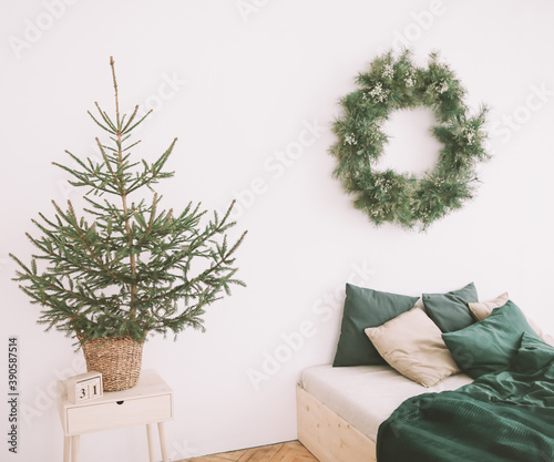 Light bedroom with a Christmas tree. Scandinavian style Christmas home interior, relaxing place. Real photo
