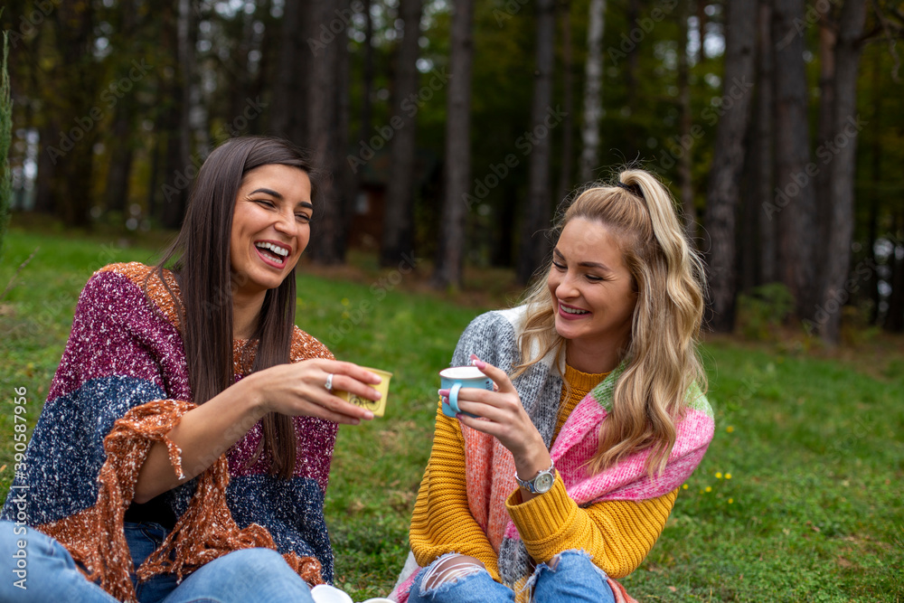 Two smiling beautiful women enjoy drinking tea.