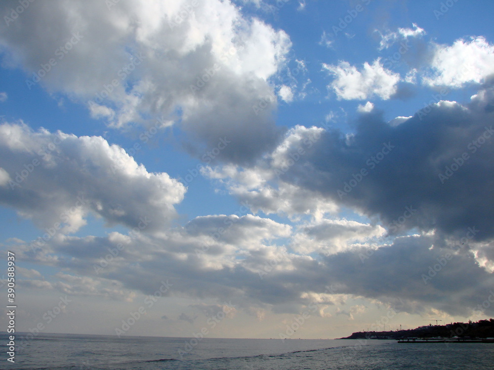 Bottom view of snow-white clouds illuminated by sunset in the blue sky over the surface of the sea. Bottom view of snow-white clouds illuminated by sunset in the blue sky over the surface of the sea.
