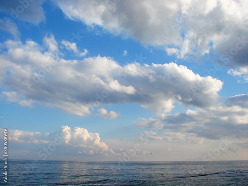 Canvas Print Bottom view of snow-white clouds illuminated by sunset in the blue sky over the surface of the sea
