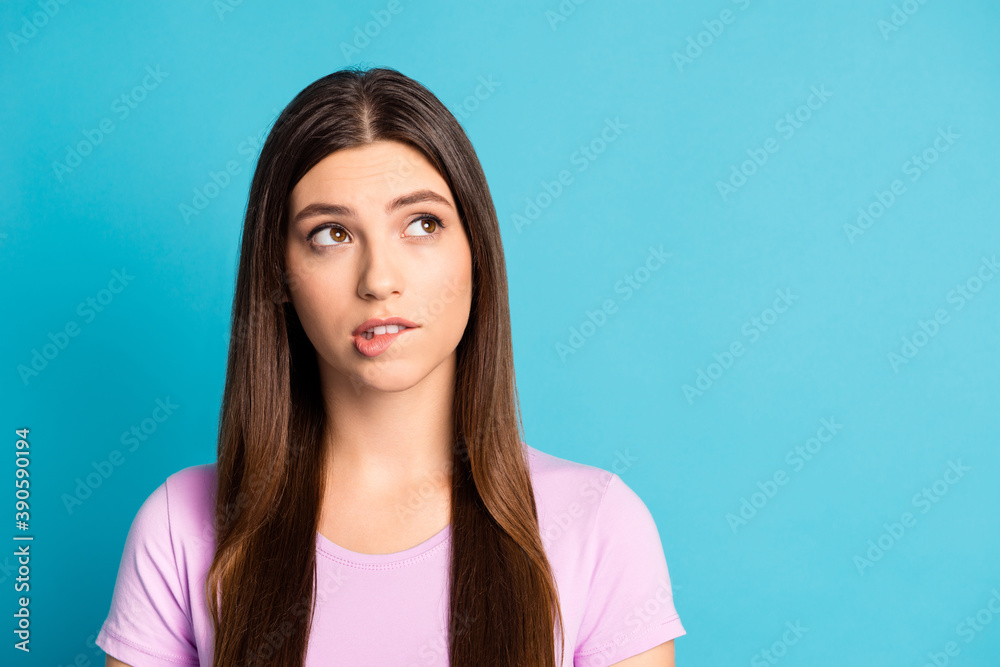 Photo portrait of serious thinking woman wear casual violet outfit look empty space biting lip isolated blue color background Photo portrait of serious thinking woman wear casual violet outfit look empty space biting lip isolated blue color background